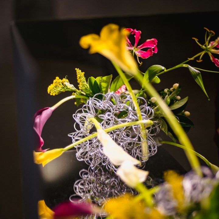 Vivid lilies and gloriosa woven through a wire form